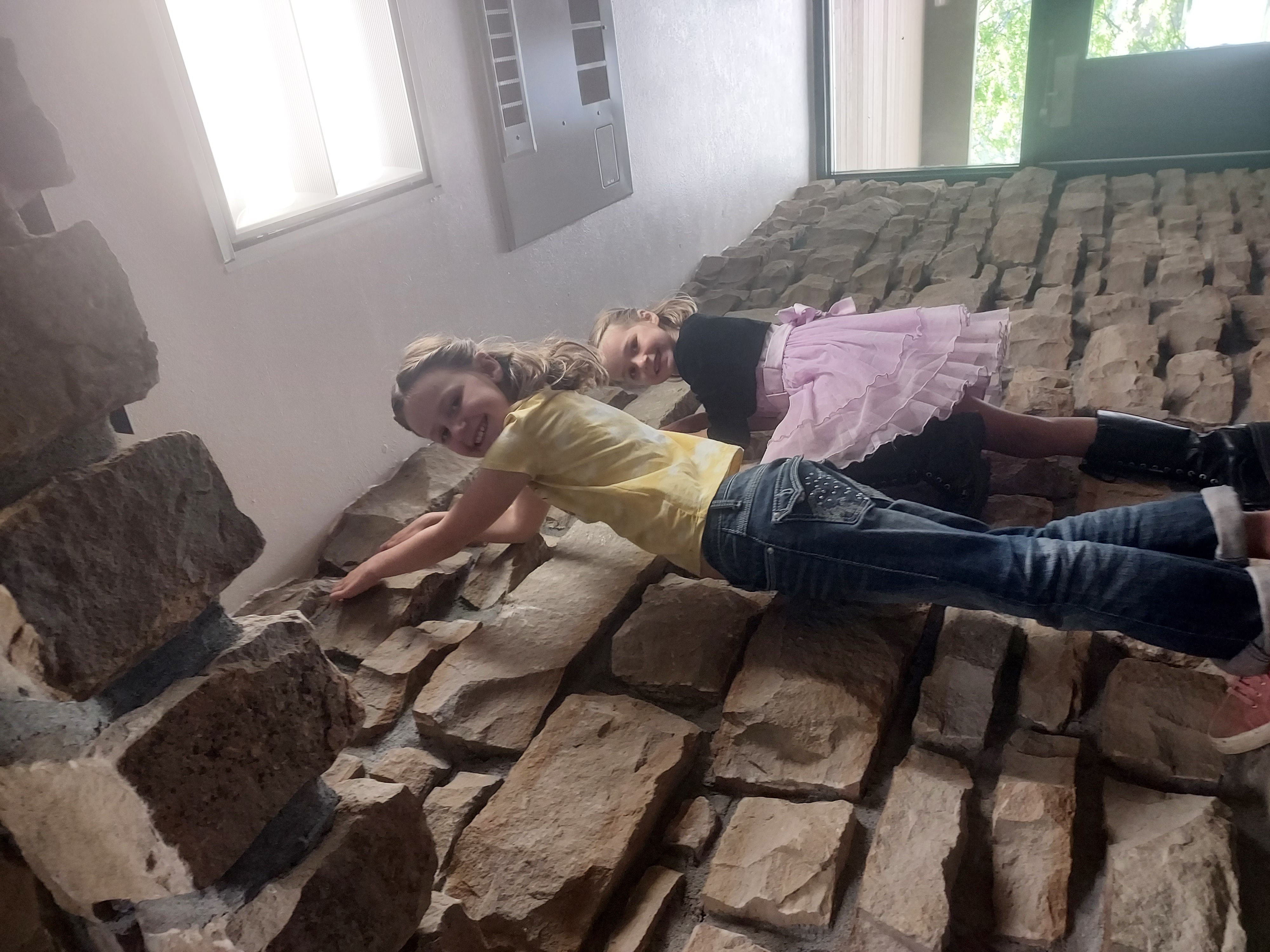 Picture of two girls smiling and climbing on a wall